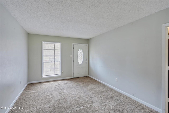 foyer with a textured ceiling, carpet flooring, and baseboards