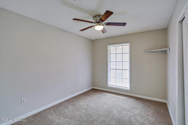 carpeted empty room featuring ceiling fan, a textured ceiling, and baseboards