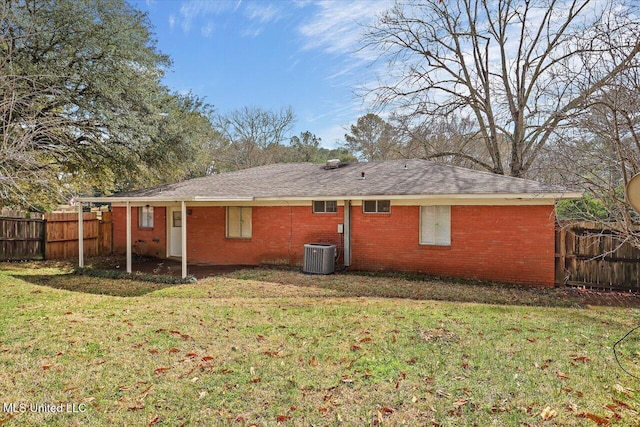 back of property with central AC unit, fence, a lawn, and brick siding