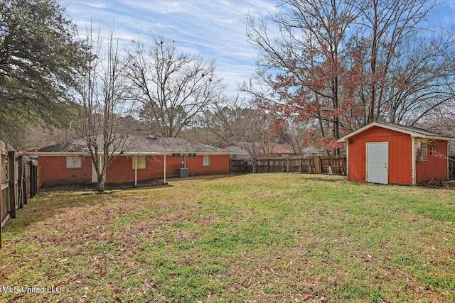 view of yard featuring an outbuilding, a fenced backyard, central AC unit, and a storage unit