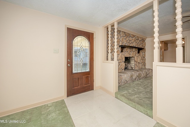 entrance foyer with crown molding, a fireplace, light colored carpet, and a textured ceiling