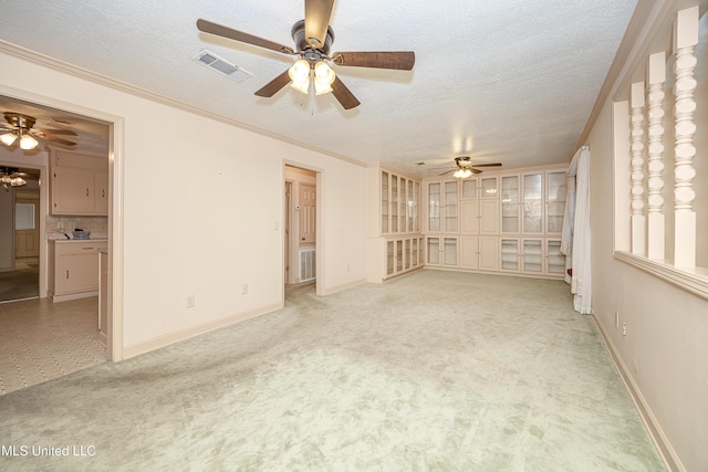 spare room featuring a textured ceiling, light colored carpet, and ornamental molding