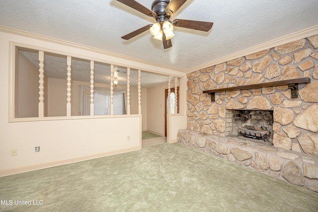 unfurnished living room featuring a textured ceiling, ceiling fan, crown molding, carpet floors, and a stone fireplace