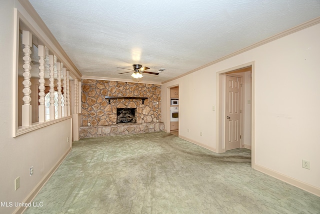 unfurnished living room with carpet flooring, ceiling fan, ornamental molding, a fireplace, and a textured ceiling