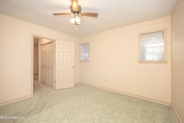 unfurnished room with ceiling fan and a textured ceiling