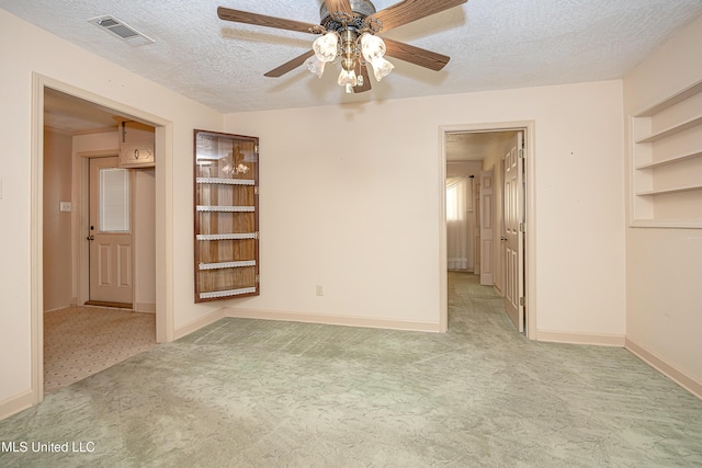 spare room with ceiling fan, light carpet, and a textured ceiling