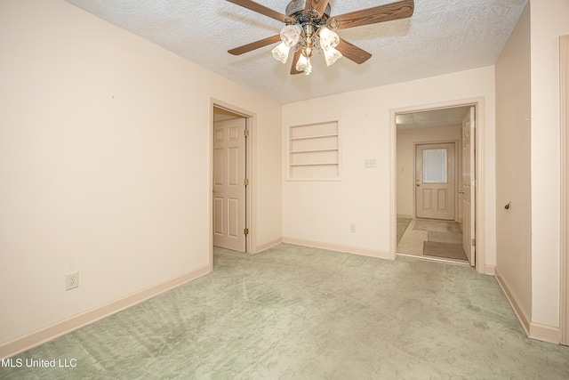 unfurnished bedroom with ceiling fan, light colored carpet, and a textured ceiling