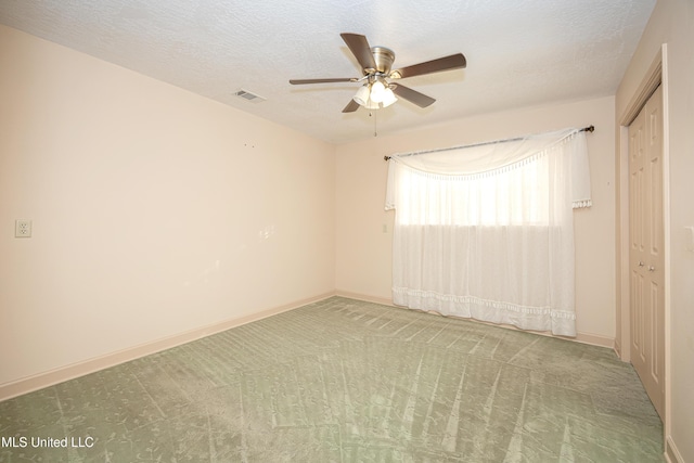 carpeted empty room featuring a textured ceiling and ceiling fan