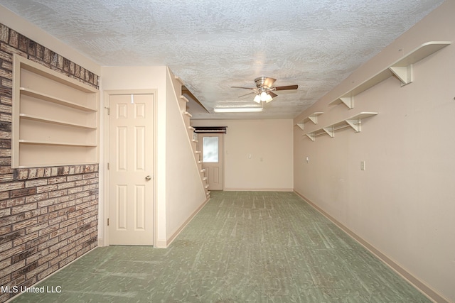 interior space featuring ceiling fan, a textured ceiling, and brick wall