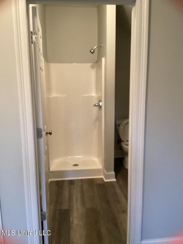 bathroom with toilet, hardwood / wood-style flooring, and a shower