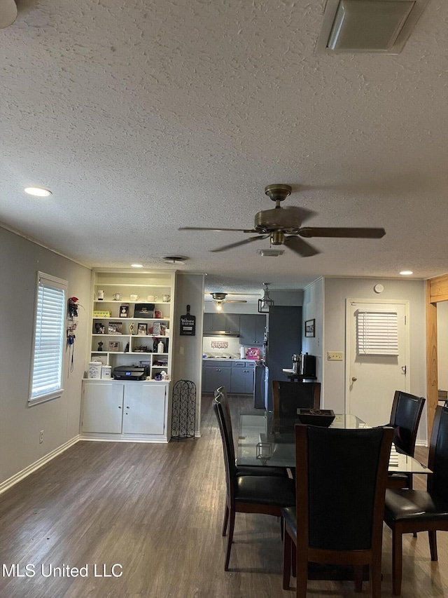 dining area featuring a textured ceiling, wood finished floors, ceiling fan, and baseboards