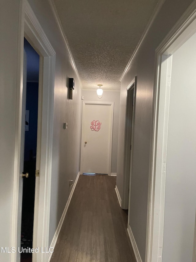 hallway featuring dark wood finished floors, baseboards, a textured ceiling, and crown molding