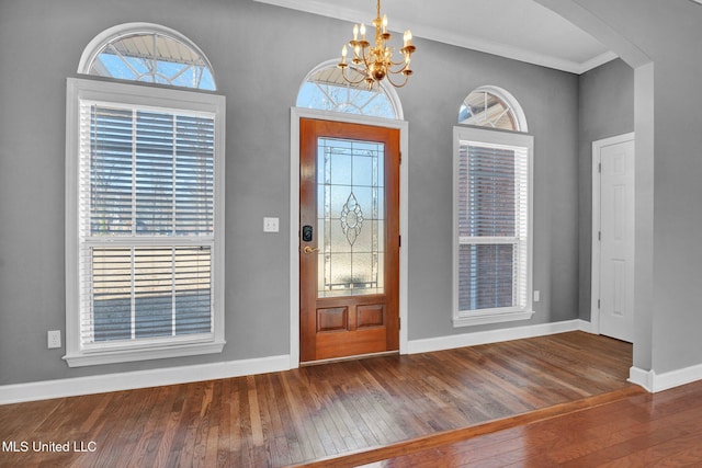 entrance foyer featuring ornamental molding, baseboards, hardwood / wood-style floors, and an inviting chandelier