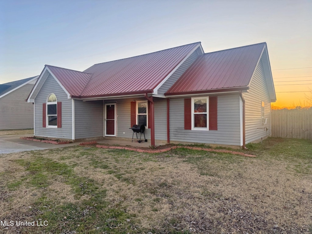 single story home featuring fence, metal roof, and a yard