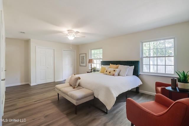 bedroom with visible vents, baseboards, multiple closets, and wood finished floors
