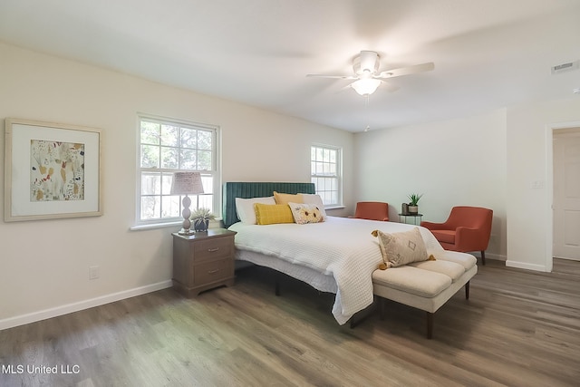 bedroom featuring wood finished floors, visible vents, a ceiling fan, and baseboards