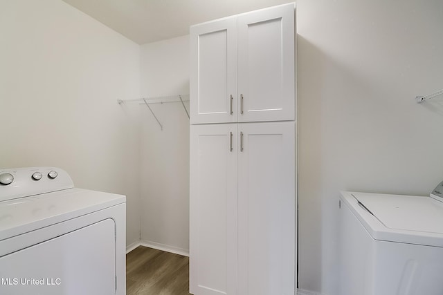 laundry area featuring cabinet space, independent washer and dryer, wood finished floors, and baseboards