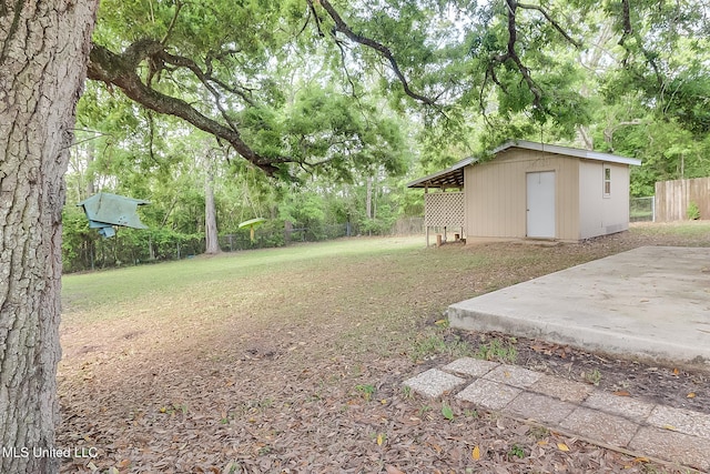 view of yard featuring a patio area, an outbuilding, and fence