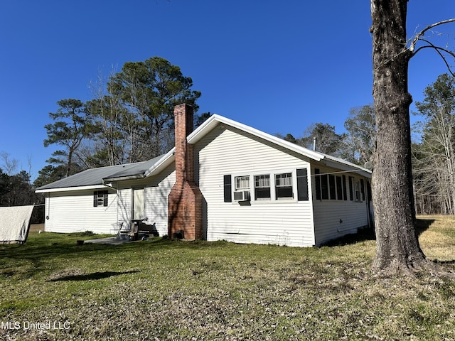 view of side of property featuring cooling unit, metal roof, a yard, and a chimney