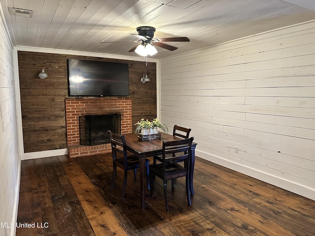 dining space with baseboards, wooden ceiling, dark wood-style flooring, wood walls, and a fireplace
