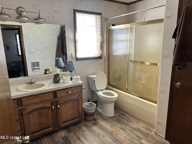 bathroom featuring toilet, combined bath / shower with glass door, wood finished floors, and vanity