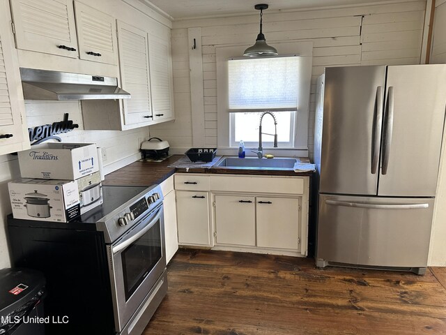 kitchen featuring dark countertops, dark wood-type flooring, freestanding refrigerator, white cabinetry, and under cabinet range hood