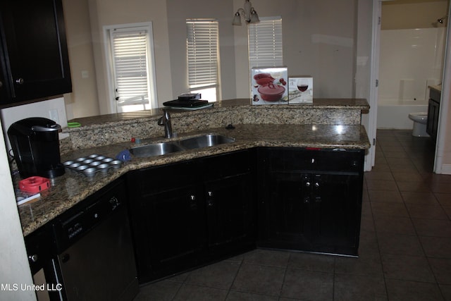 kitchen featuring sink, dark tile patterned floors, dishwasher, and stone counters