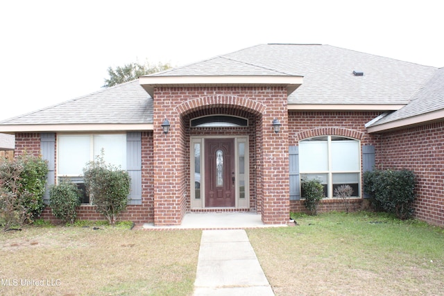 view of exterior entry featuring a lawn