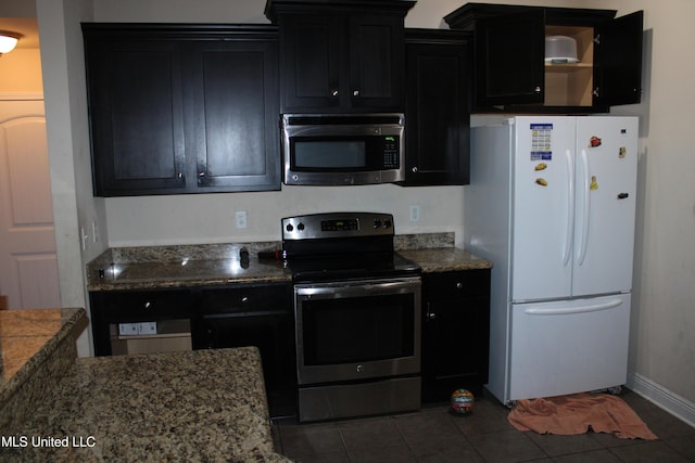 kitchen with stone counters, appliances with stainless steel finishes, and dark tile patterned floors