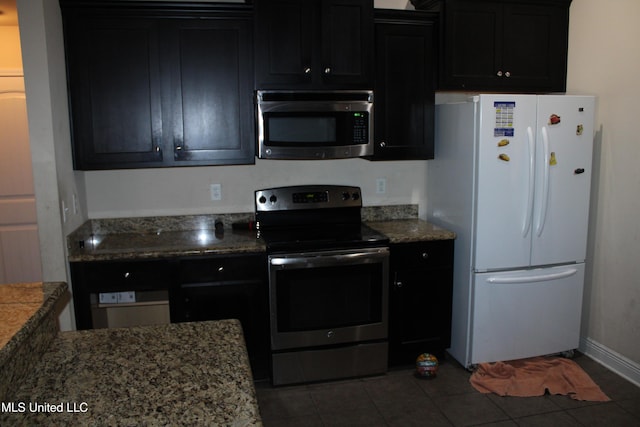 kitchen with stainless steel appliances, dark tile patterned flooring, and light stone countertops