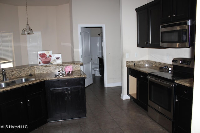 kitchen featuring appliances with stainless steel finishes, decorative light fixtures, sink, and dark tile patterned floors