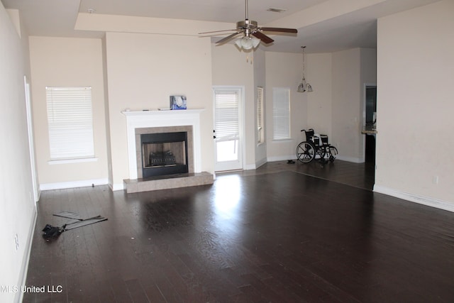 unfurnished living room with ceiling fan, a fireplace, dark hardwood / wood-style flooring, and a towering ceiling