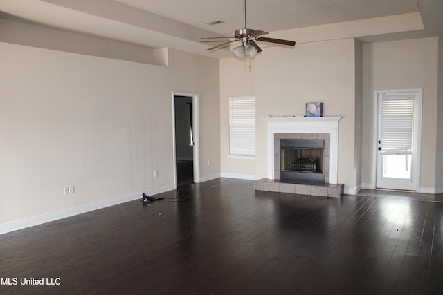 unfurnished living room with a fireplace, a towering ceiling, dark wood-type flooring, and ceiling fan