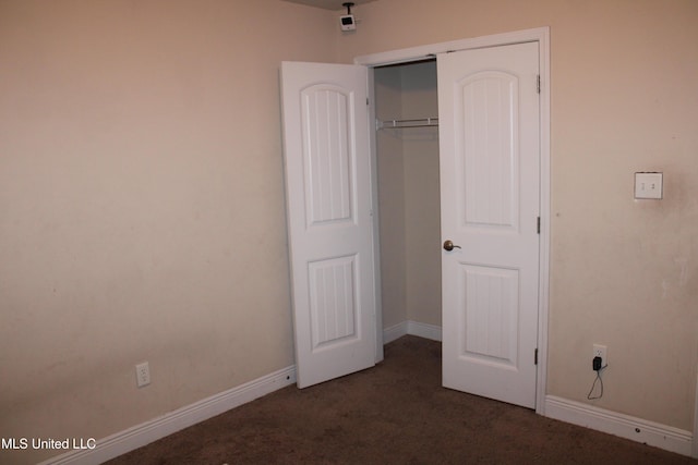 unfurnished bedroom featuring a closet and dark colored carpet