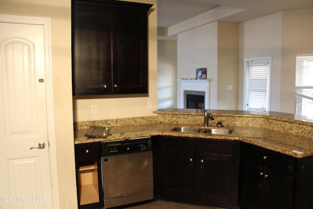 kitchen featuring light stone counters, stainless steel dishwasher, kitchen peninsula, and sink