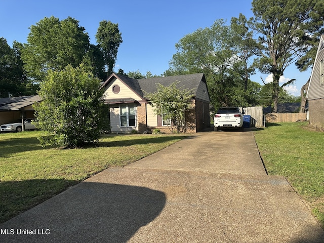 view of front of house with brick siding, driveway, fence, and a front yard