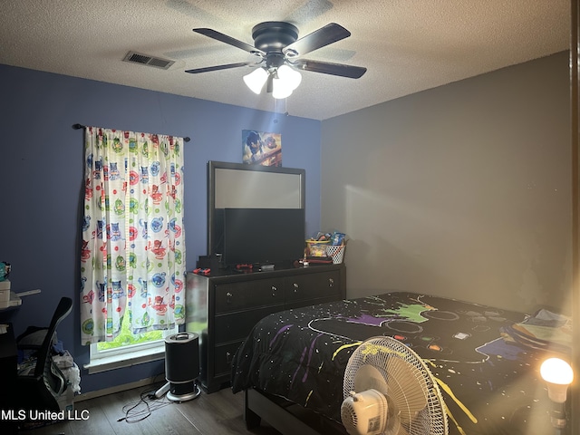 bedroom featuring a textured ceiling, visible vents, wood finished floors, and a ceiling fan