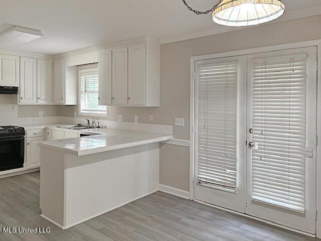 594 Acorn Ln, Brandon, MS 39047 - kitchen featuring stove, a peninsula, ornamental molding, light wood-style flooring, and white cabinets