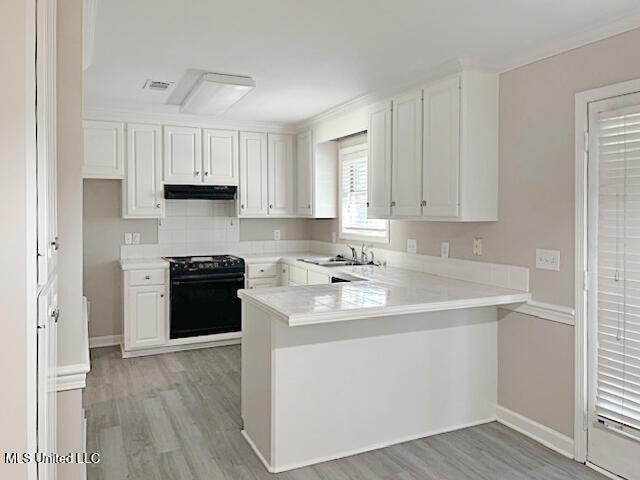 594 Acorn Ln, Brandon, MS 39047 - kitchen with stove, a peninsula, light wood-style flooring, under cabinet range hood, and white cabinets