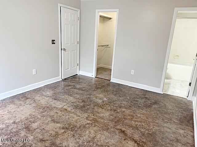 594 Acorn Ln, Brandon, MS 39047 - unfurnished bedroom featuring a spacious closet, finished concrete floors, a closet, and ensuite bath