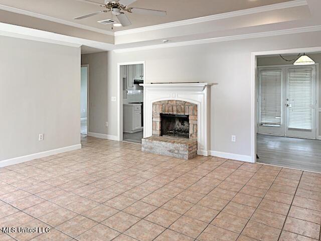 594 Acorn Ln, Brandon, MS 39047 - unfurnished living room featuring a raised ceiling, ceiling fan, crown molding, a fireplace with raised hearth, and light tile patterned floors