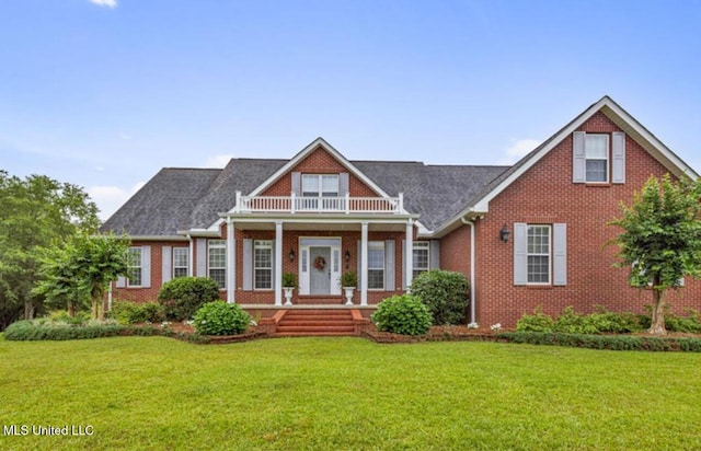 view of front facade featuring a front yard, covered porch, brick siding, and a balcony