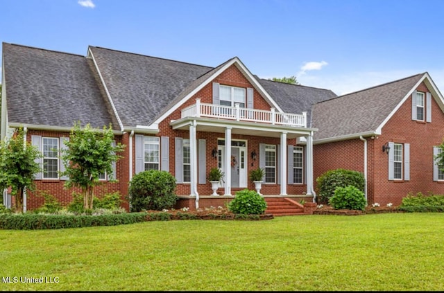 view of front of house featuring brick siding, a shingled roof, a balcony, covered porch, and a front yard