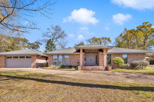 view of front of house featuring brick siding, concrete driveway, a garage, and a front lawn