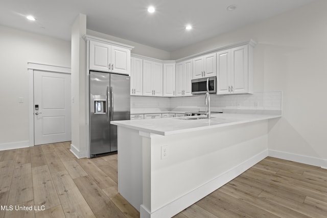 124 Court St, Bay Saint Louis, MS 39520 - kitchen with stainless steel appliances, light countertops, backsplash, a peninsula, and light wood-style flooring
