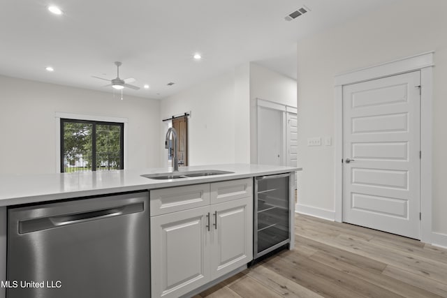 124 Court St, Bay Saint Louis, MS 39520 - kitchen featuring stainless steel dishwasher, beverage cooler, a barn door, light wood finished floors, and recessed lighting