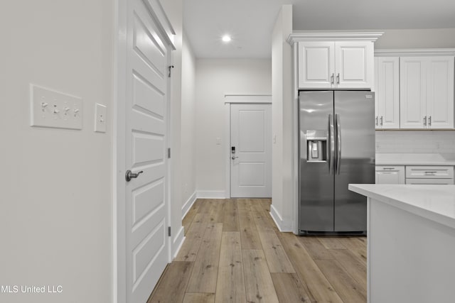 124 Court St, Bay Saint Louis, MS 39520 - kitchen featuring stainless steel fridge with ice dispenser, light countertops, white cabinets, light wood-style floors, and recessed lighting