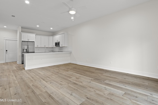 124 Court St, Bay Saint Louis, MS 39520 - kitchen featuring appliances with stainless steel finishes, recessed lighting, a peninsula, white cabinets, and light wood finished floors