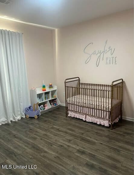 361 Cherry Bark Ln, Courtland, MS 38620 - bedroom featuring wood finished floors, a crib, and baseboards