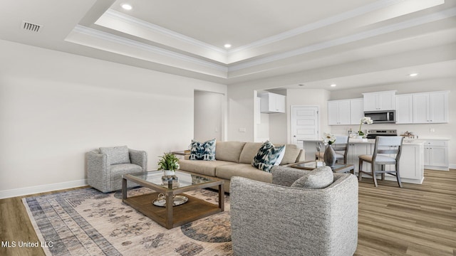 living room with crown molding, hardwood / wood-style floors, and a tray ceiling